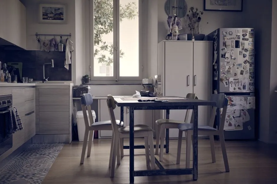 Reader at a kitchen table with a coffee, reading the day's history email on a phone in morning light