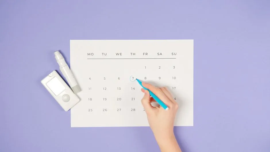Hand tapping a date on a tablet calendar beside a notebook and pen